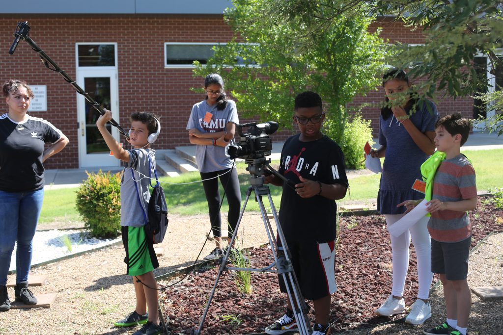 Students running boom, camera, and slate on an outdoor shoot