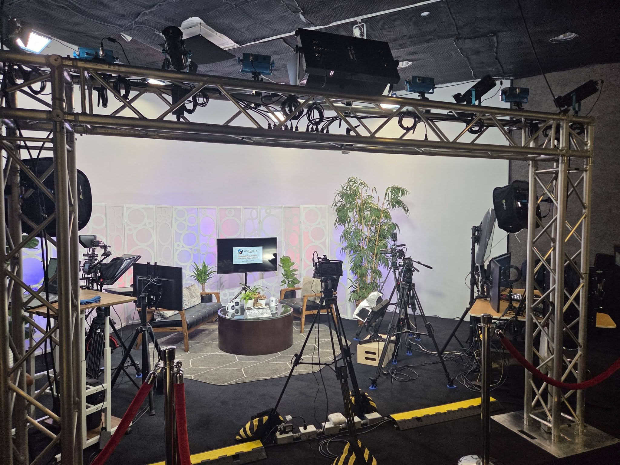 The MI North podcast studio with a lighting truss, multiple cameras, and a lounge set