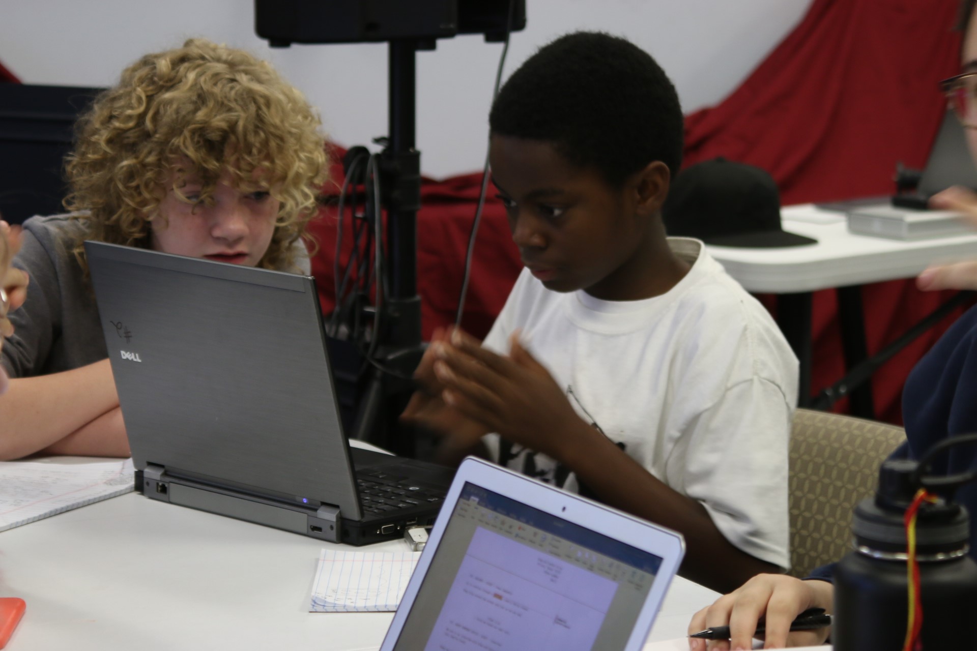 Two campers writing a screenplay together on laptops